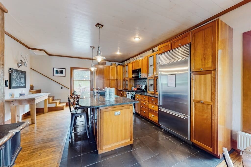A spacious kitchen with wooden cabinets, a stainless steel refrigerator, and a central island.