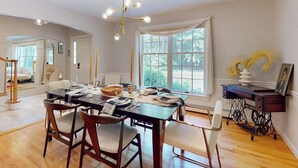 A dining area with a wooden table, chairs, and a chandelier. - Woodland Home With Screened Porch, 2 Living Rooms - Near Historic Waterfront (Bath)