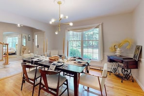 A dining area with a wooden table, chairs, and a chandelier. - Woodland Home With Screened Porch, 2 Living Rooms - Near Historic Waterfront (Bath)