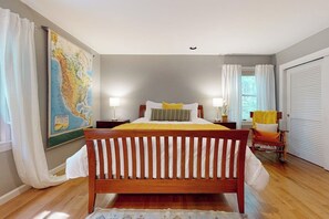 A bedroom with a wooden bed, a map on the wall, a chair, and a window with curtains. - Woodland Home With Screened Porch, 2 Living Rooms - Near Historic Waterfront (Bath)