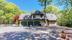 Ett tvåvåningshus med ett garage, omgivet av träd och en uppfart.
