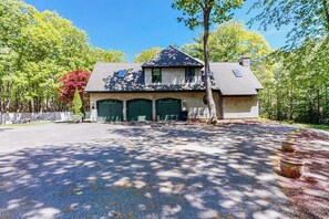 A two-story house with a garage, surrounded by trees and a driveway. - Lions Gate (Ellsworth)