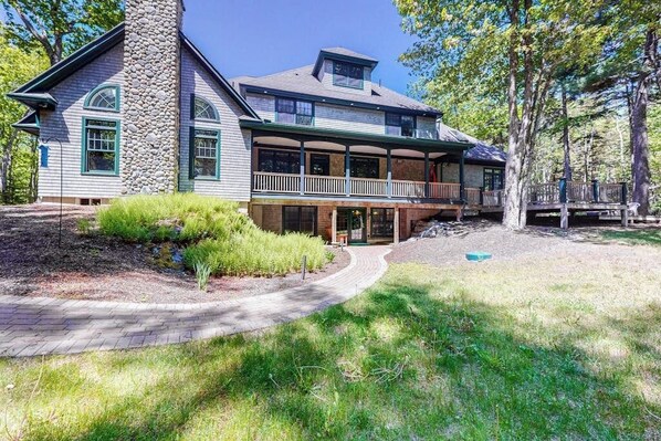 A two-story house with a stone chimney, a covered porch, and a landscaped yard. - Lions Gate (Ellsworth)