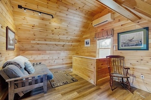 A wooden cabin interior with a bed, a rocking chair, a bench, and a window with a view. - Lakeview Getaway - Trailer Parking, Walk to Ramp, Dogs Welcome & High-speed Wifi (Greenville)