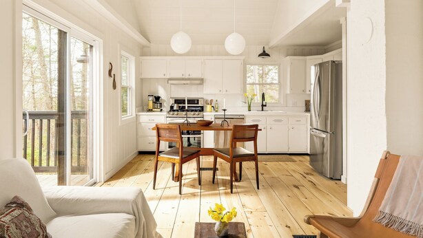 Una cocina amplia con gabinetes blancos, una mesa de comedor y sillas.