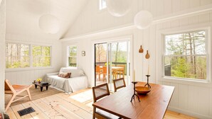 Una habitación amplia con una mesa de comedor de madera, un sofá y una silla. Cuenta con ventanas grandes y vistas al exterior.