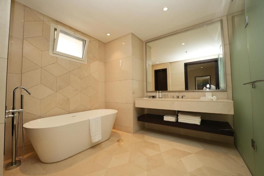 A modern bathroom with a freestanding bathtub, a large mirror, and a vanity with a shelf.