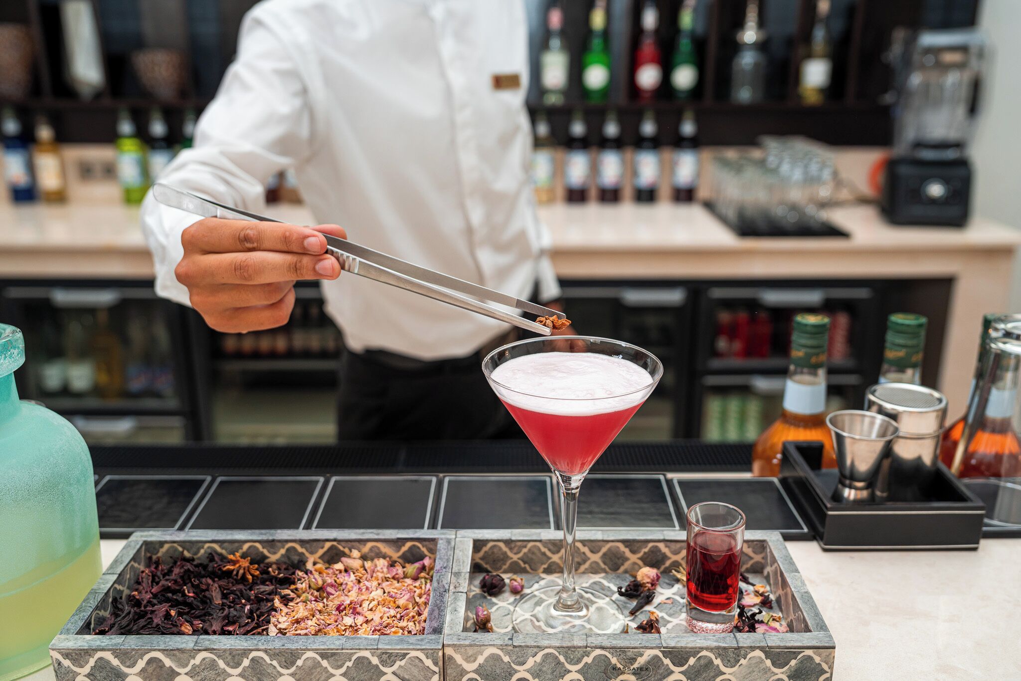 A bartender preparing a cocktail with a martini glass on a bar counter.