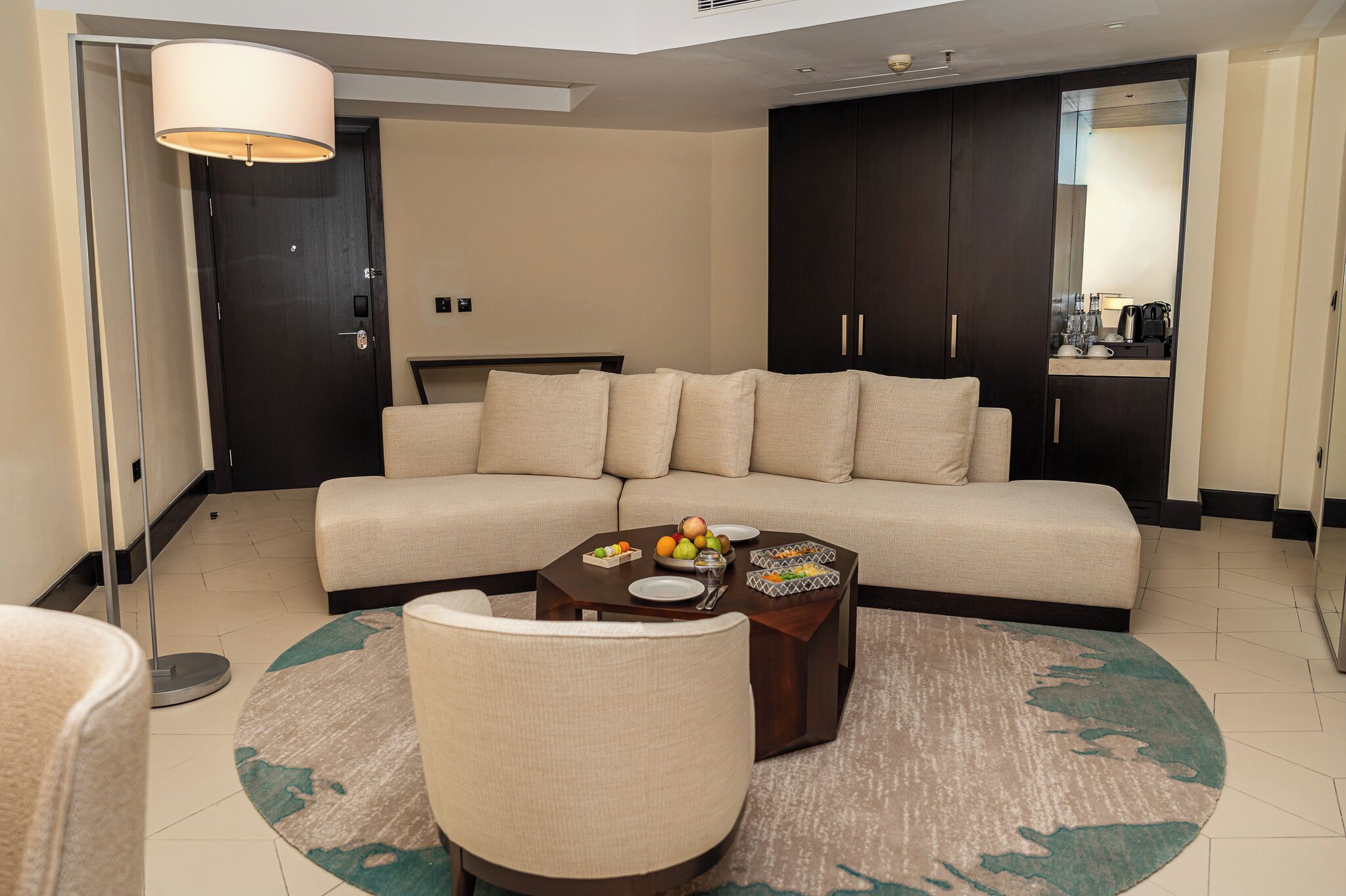 A modern living room with a sofa, a coffee table with fruits, and a lamp.