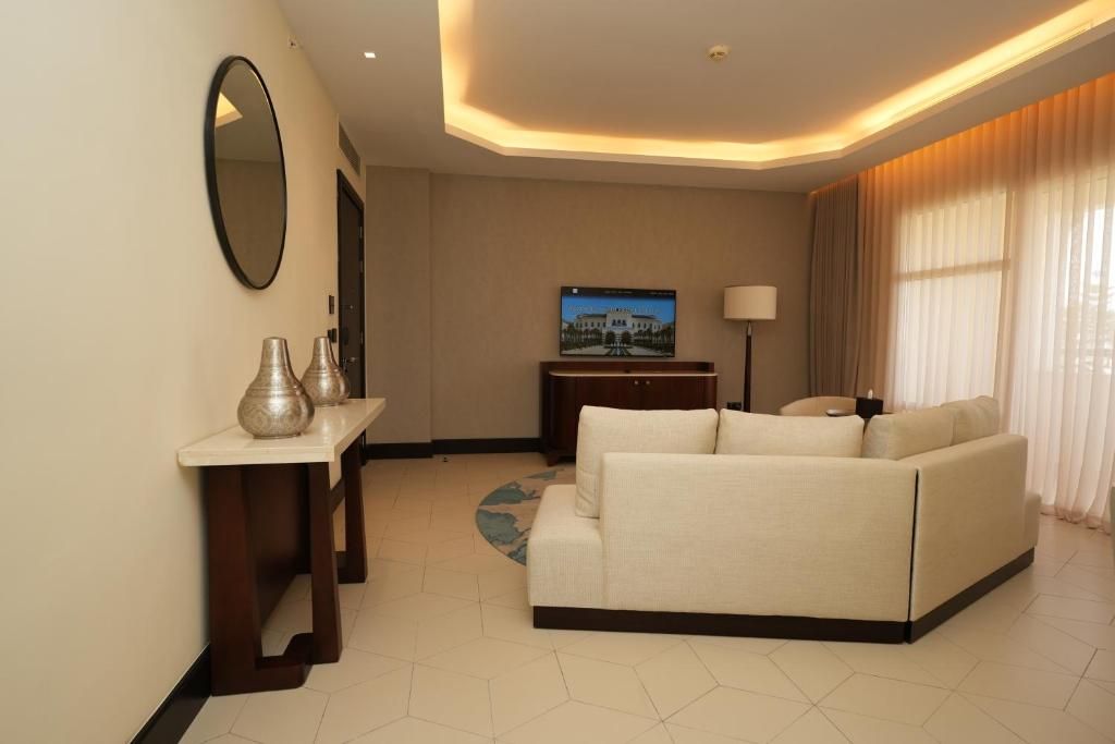 A modern living room with a sofa, a television, a lamp, and a decorative mirror.