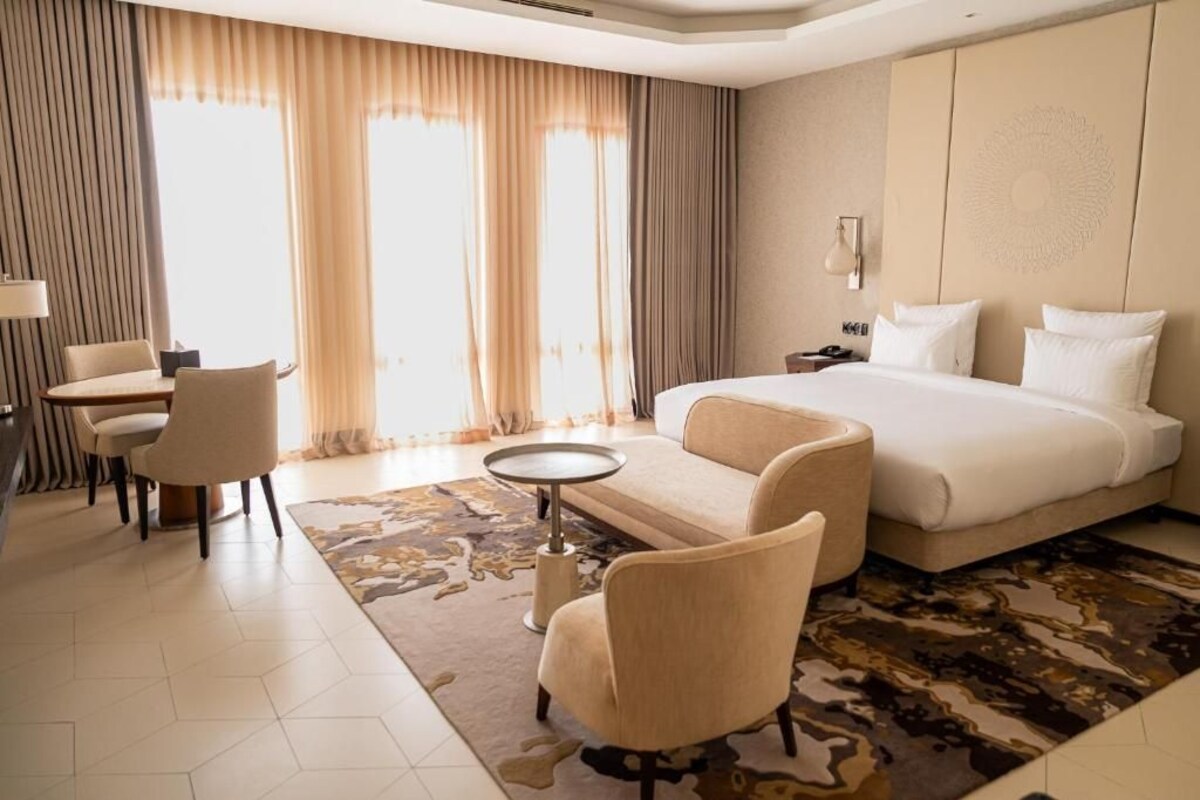 Una habitación de hotel con una cama, un escritorio, una silla y una pequeña mesa.