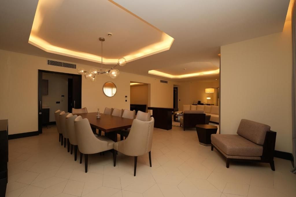 A modern dining area with a large table and chairs, a sofa, and a lamp.