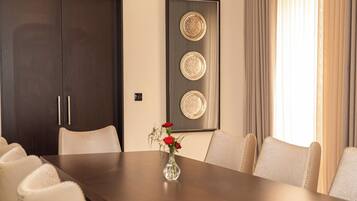 A conference room with a long table, six chairs, a vase with flowers, and decorative plates on the wall.