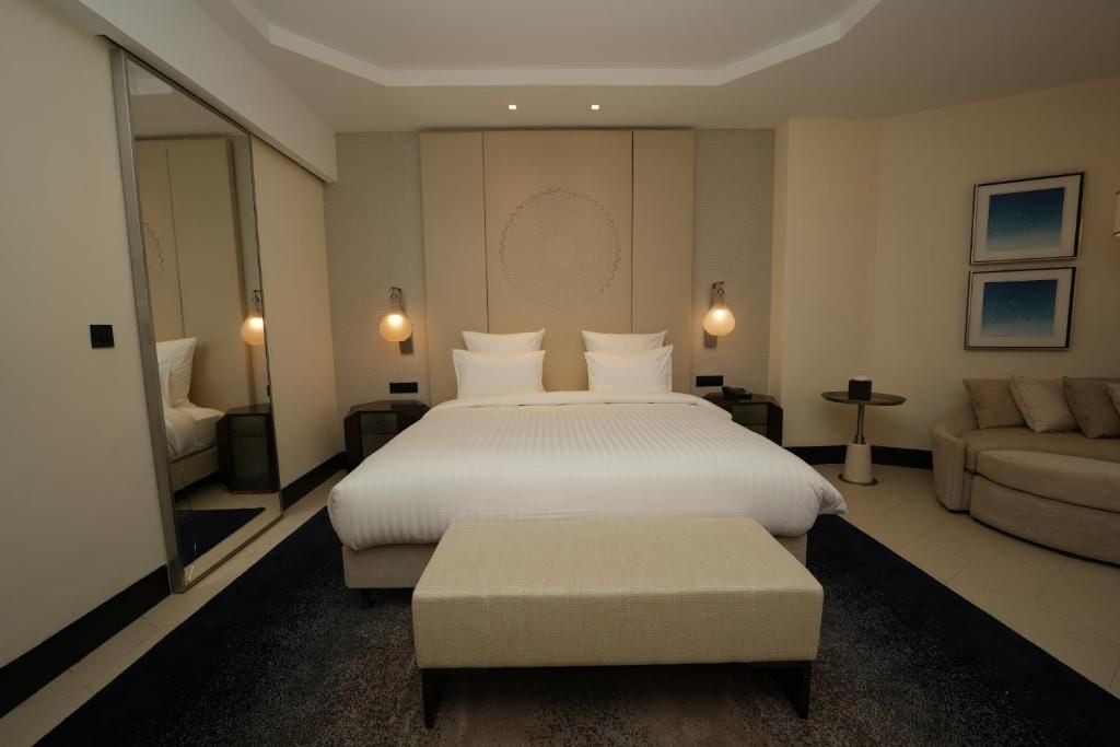 A hotel room with a large bed, a sitting area, a small table, and a sofa.