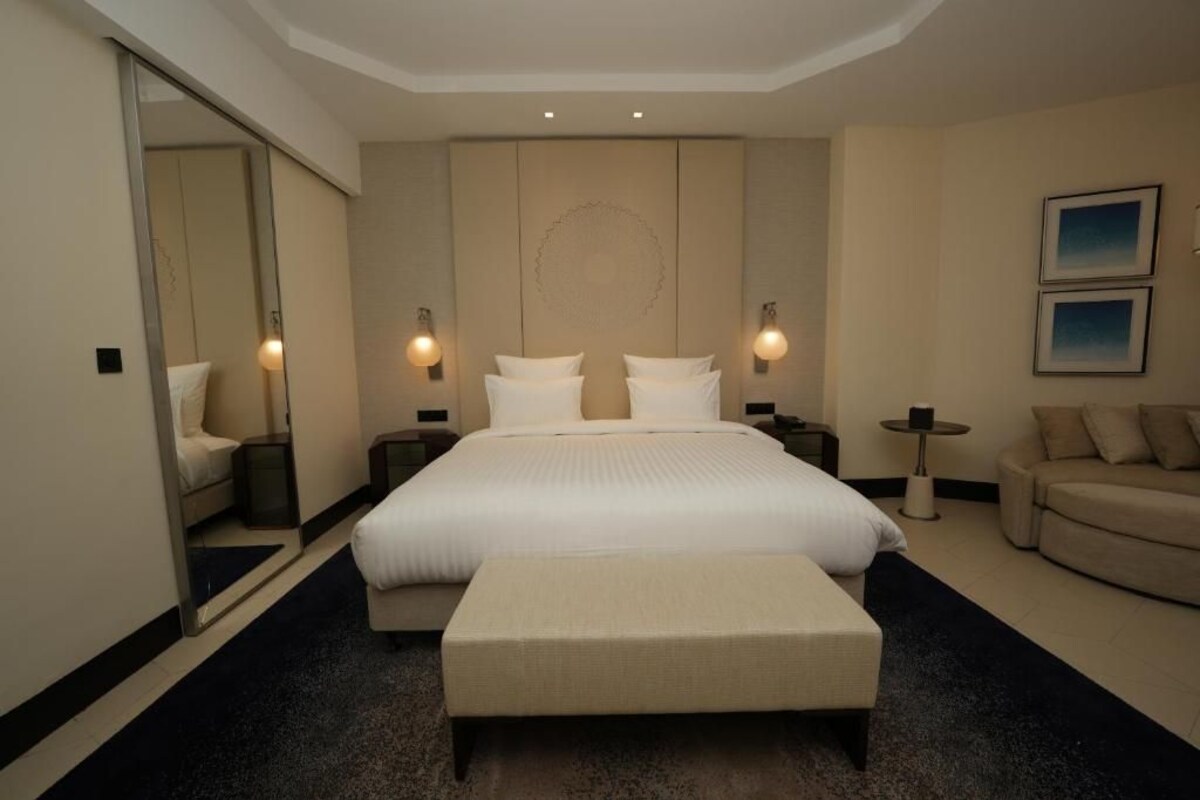 Habitación de hotel con una cama grande, una zona de estar, una mesita pequeña y un sofá.