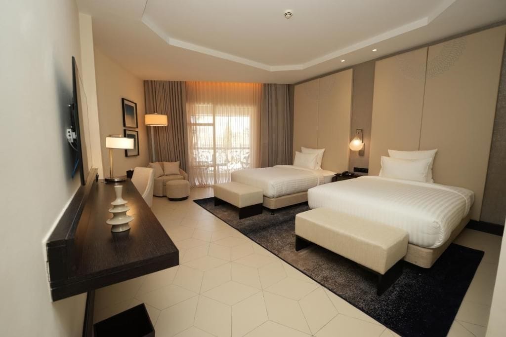 A hotel room with a bed, two bedside tables, a desk, and a chair.