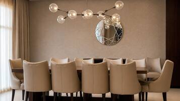 Un comedor con una mesa redonda, seis sillas, una lámpara moderna y un espejo decorativo en la pared.