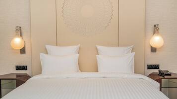A hotel room with a large bed, two bedside tables, a wall-mounted decorative pattern, and wall sconces.