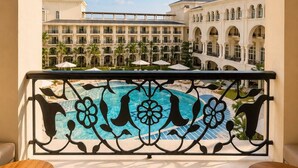 A balcony with a pool view, two wooden tables, and a decorative railing.