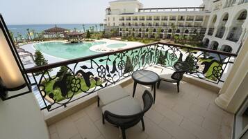 A balcony with a pool view, outdoor seating, and a building with balconies.