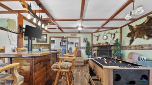 A bar area with wooden stools, a pool table, and a television.