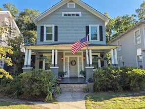 A two-story house with a porch, a flag, and a wreath on the door.