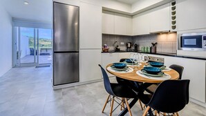 Una cocina moderna con microondas integrado, un refrigerador de acero inoxidable y un comedor con mesa redonda y sillas.