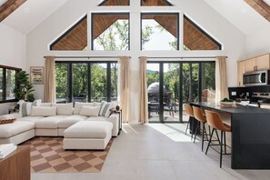 Un'ampia zona giorno con un grande divano a forma di L, una cucina dotata di elettrodomestici moderni e ampie finestre con vista sull'esterno.