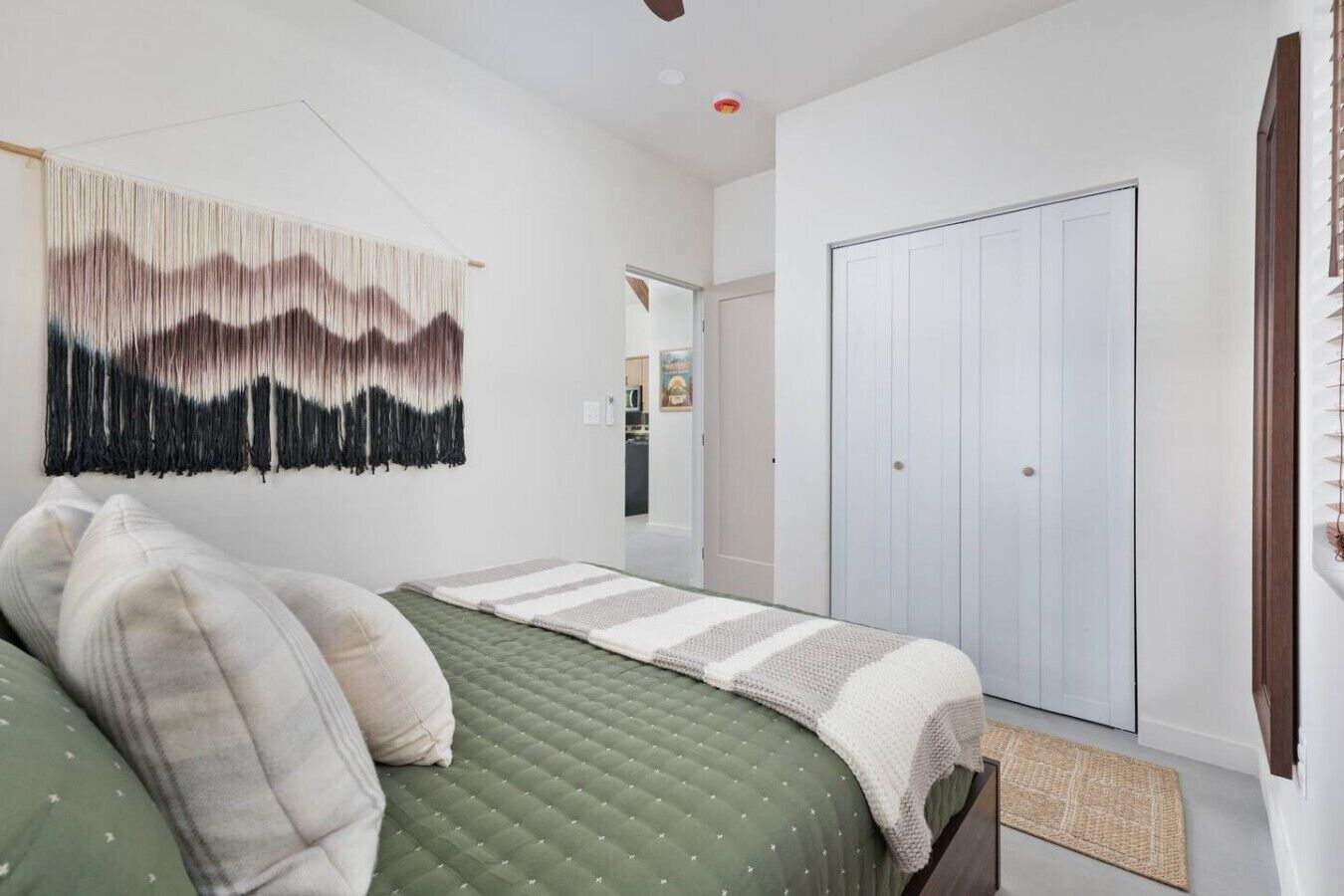 Ein Schlafzimmer mit einem Bett, einer Wandteppich, einem Kleiderschrank und einer Tür zu einem anderen Raum.