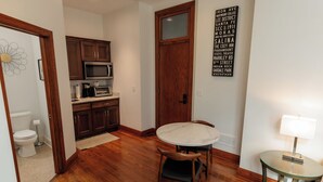 Una cocina compacta con muebles de madera, un microondas y un comedor con mesa y sillas.