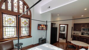Un dormitorio con una cama grande, un banco de madera, una mesita pequeña y un televisor.
