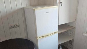 Een kleine keuken met een witte koelkast, een tafeltje en een kast.