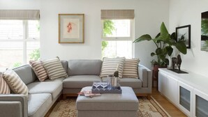 A living room with a sectional sofa, a coffee table, a large plant, and artwork on the walls. - The Iconic Portobello Mews House (Greater London)