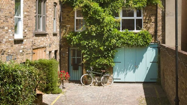 A narrow alleyway with a brick building, a bicycle, and a blue gate. - The Iconic Portobello Mews House (Greater London)