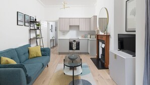 Ein modernes Wohnzimmer mit Sofa, Couchtisch, Kamin und einer Küche im Hintergrund.