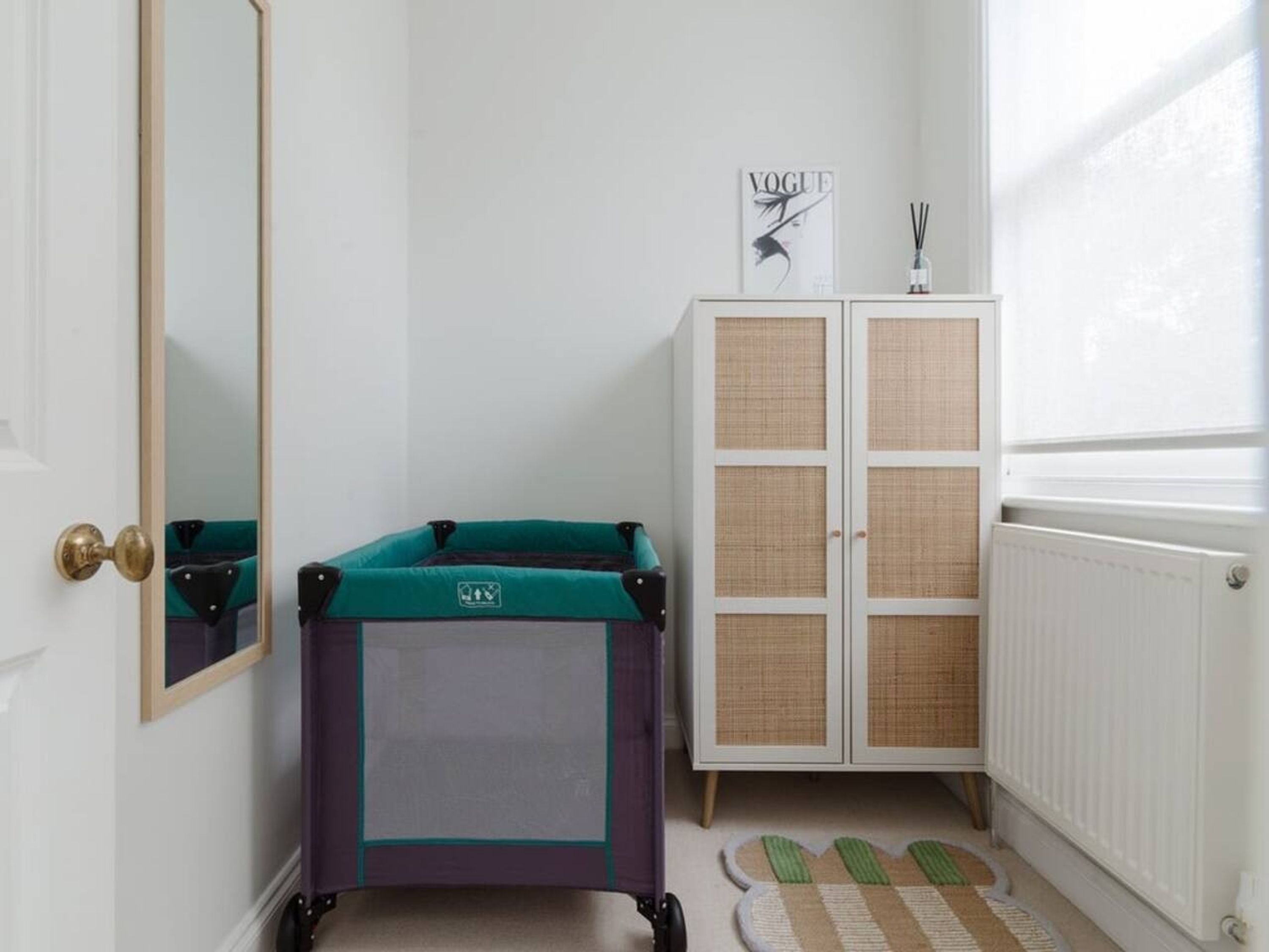 A child's playpen, a wardrobe, a mirror, and a window with a view.