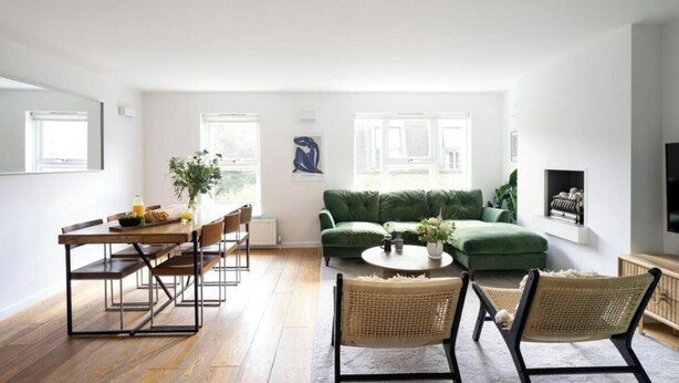 Un salón amplio con un sofá verde, una mesa de comedor con sillas y una chimenea.