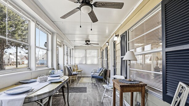 A sunroom with a dining table, chairs, a sofa, and a ceiling fan. - Charming 6BR Colonial Beach Retreat, Walk to the Beach (Colonial Beach)