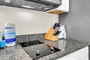 Eine Küche mit einer Granit Arbeitsplatte, einem Gasherd, einem Messerset und einer Tüte Küchentücher.