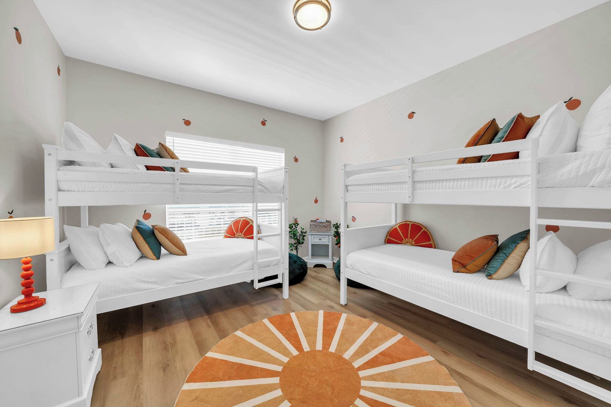 Ein Zimmer mit zwei Etagenbetten, einem Nachttisch mit Lampe und einem dekorativen Teppich.