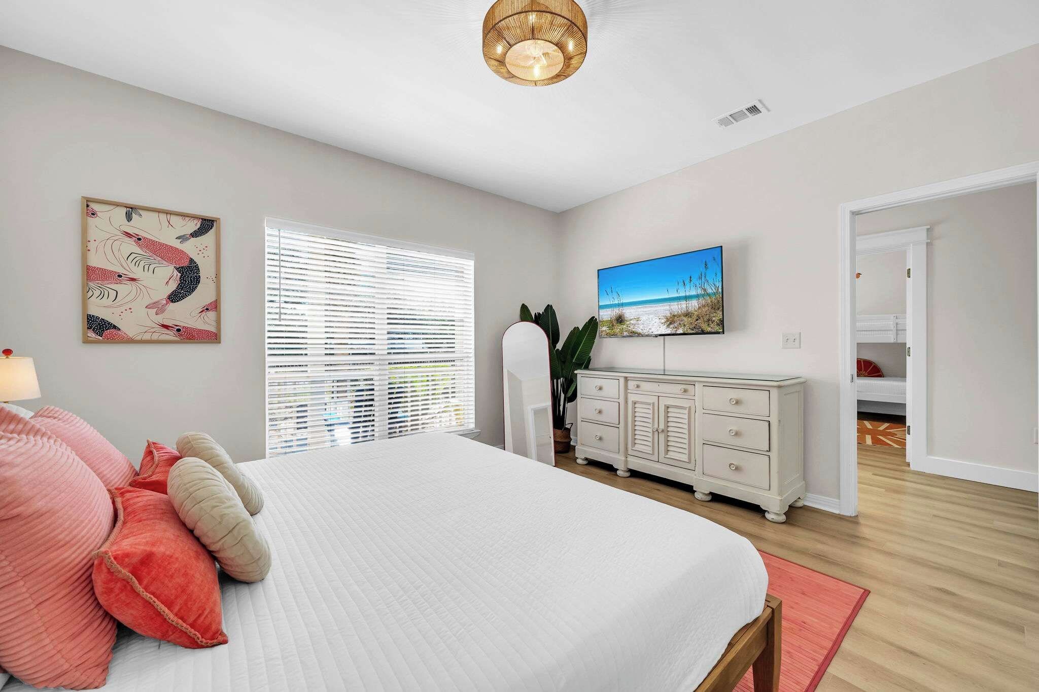 A bedroom with a bed, a dresser, a television, and a window with blinds.