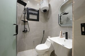 Une salle de bain moderne équipée de toilettes, d’un lavabo, d’une douche et d’un miroir encadré.