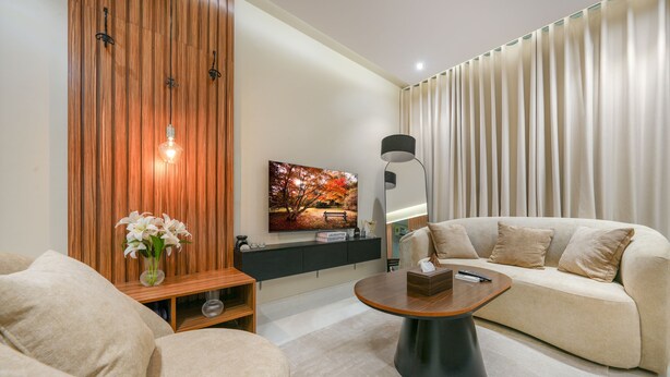 A modern living room with a sofa, coffee table, and a painting on the wall. - Furnished Studio in Al-Aqiq (Riyadh)