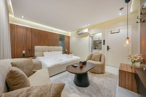 A modern hotel room with a bed, a sofa, a coffee table, and a desk.