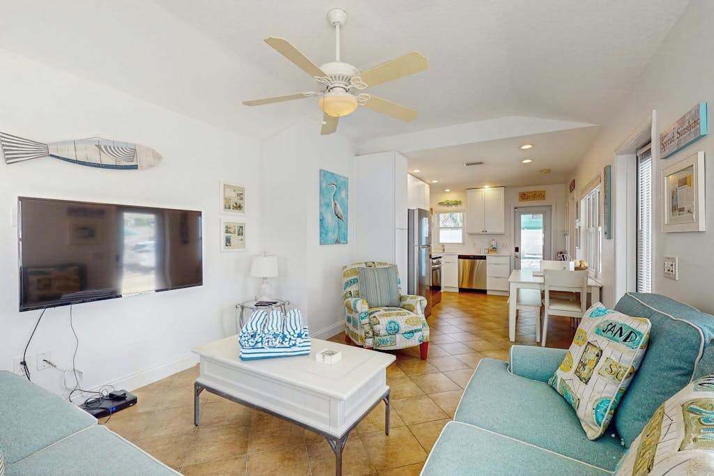 A living room with a TV, a ceiling fan, a coffee table, and a sofa.