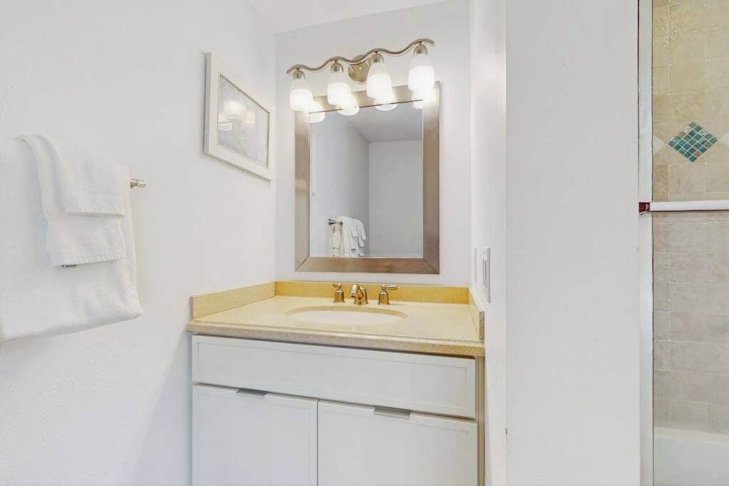 Une salle de bain avec un lavabo, un miroir et un porte-serviettes.
