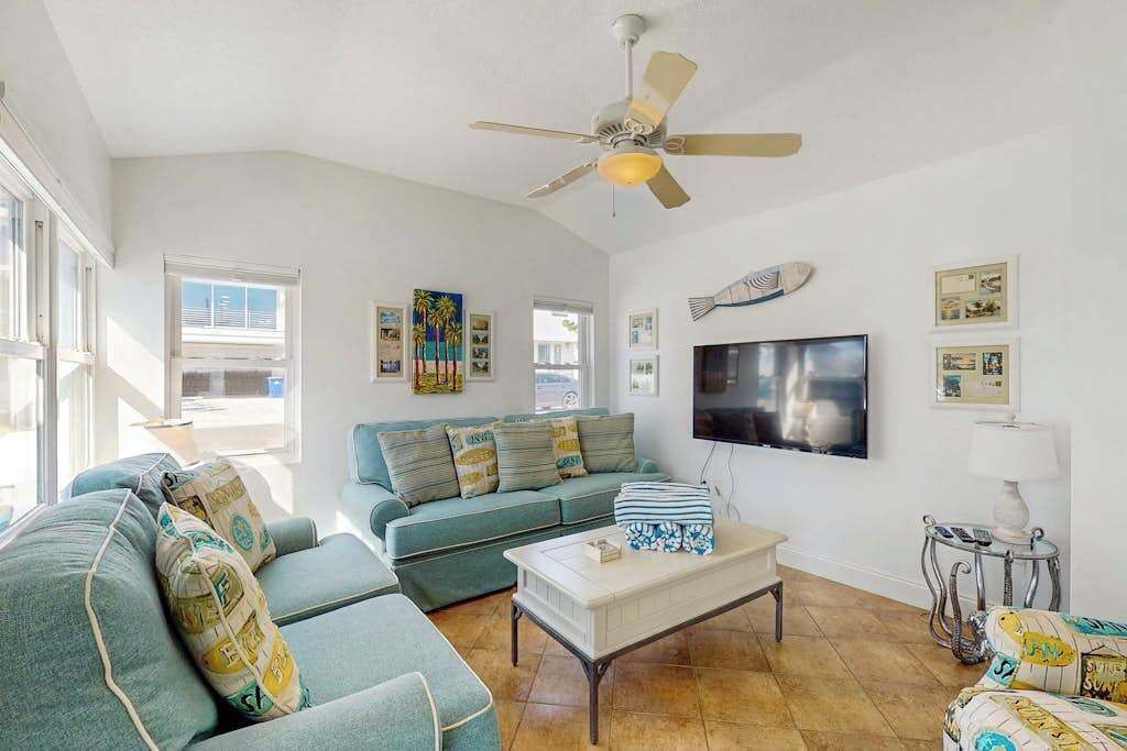 A living room with a ceiling fan, a flat-screen TV, a sofa, a coffee table, and a lamp.
