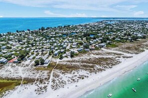Ein Luftbild eines Wohngebiets an der Küste mit Häusern, einem Strand und klarem, blauem Wasser.