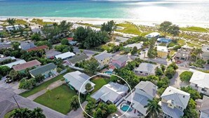 Oversigtsbillede af et kystnære boligområde med huse, en strand og en swimmingpool.