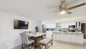 Eine moderne Küche mit weißen Schränken, einer zentralen Kochinsel und einem Deckenventilator.